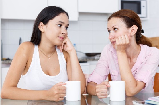 Madre e hija hablando con una taza en la mano.