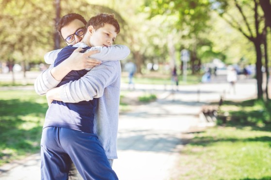 Joven con autismo abrazando a su padre en un parque