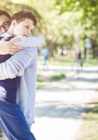 Joven con autismo abrazando a su padre en un parque